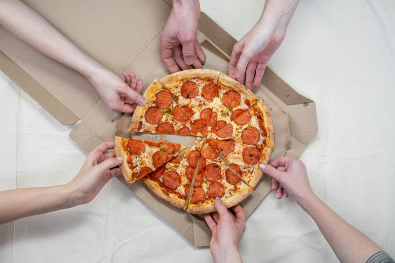 Person Holding a Pizza With Cheese