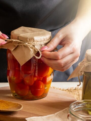 Young woman cans and pickles vegetables. Fermentation process of tomatoes. Healthy eco food.