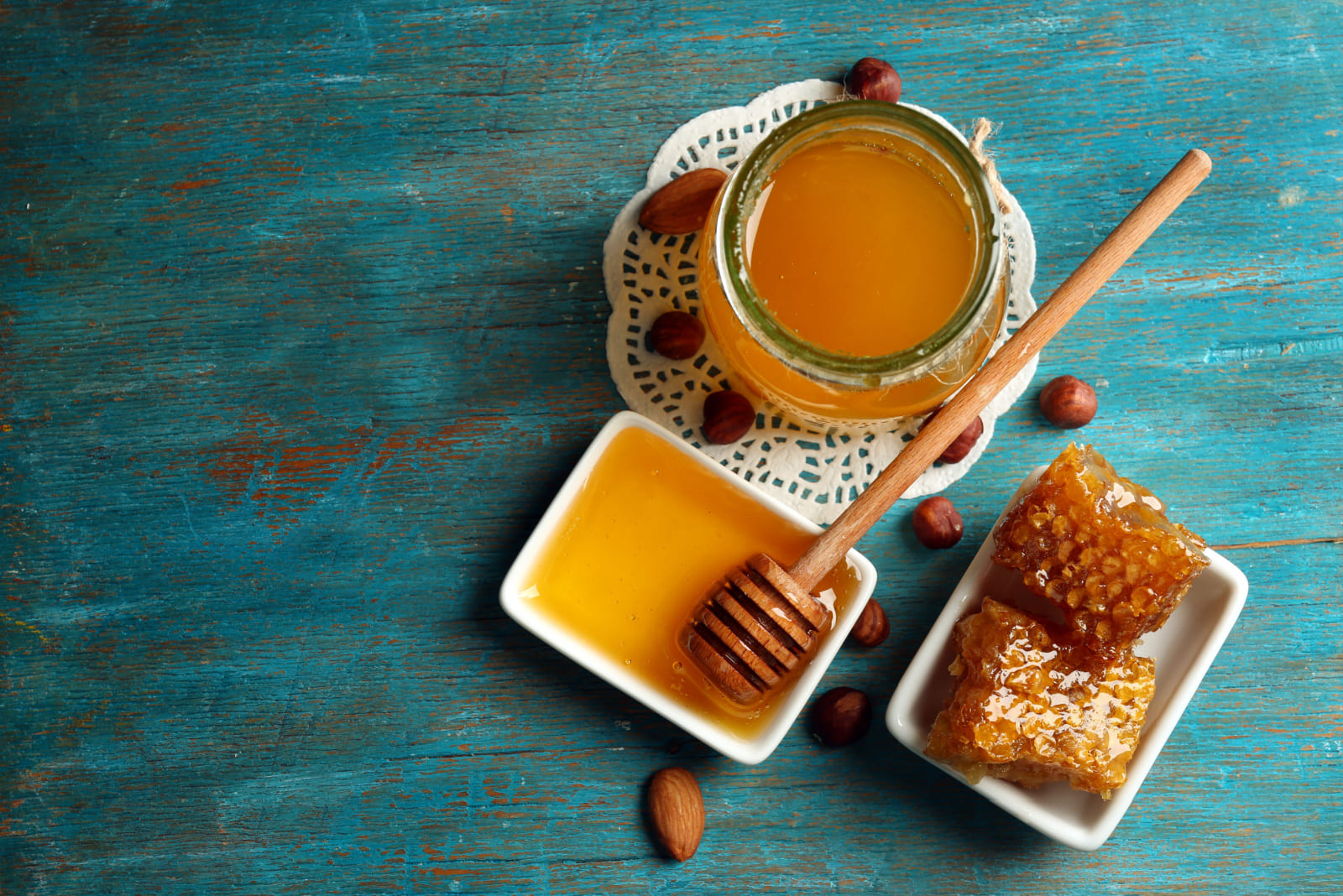 Honeycomb, glass pot with honey and nuts on color wooden background