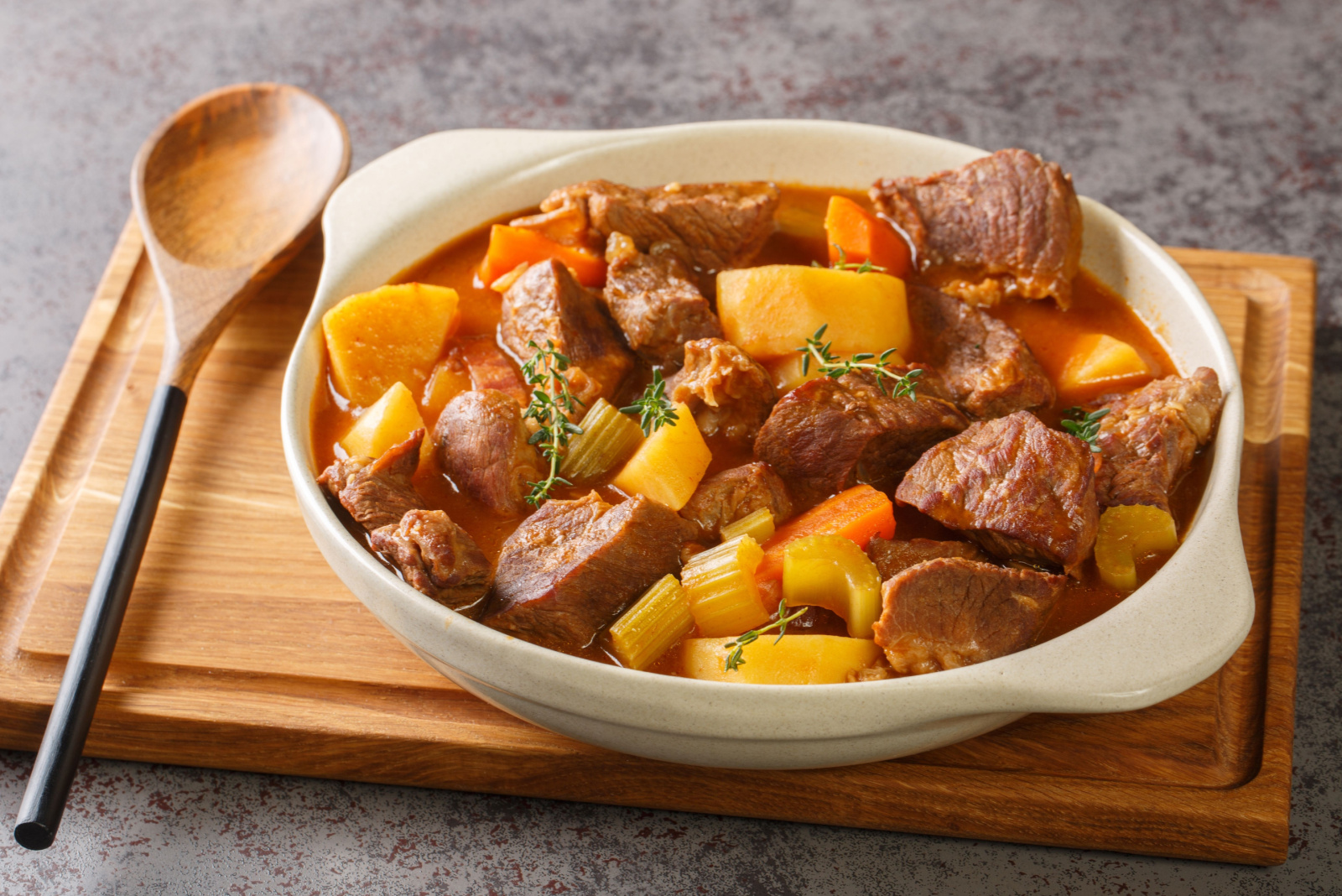 Hearty Irish inspired beef stew made with garlic, stock, Guinness, bacon, potatoes, carrots, and onions closeup in the pot on the table. Horizontal 