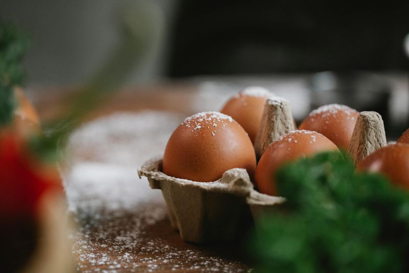 Eggs in container for cooking on wooden table