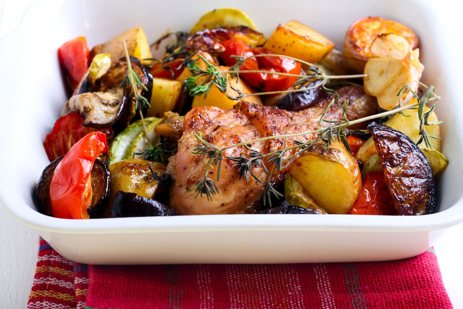 Baked vegetables and chicken drumstick in baking tin