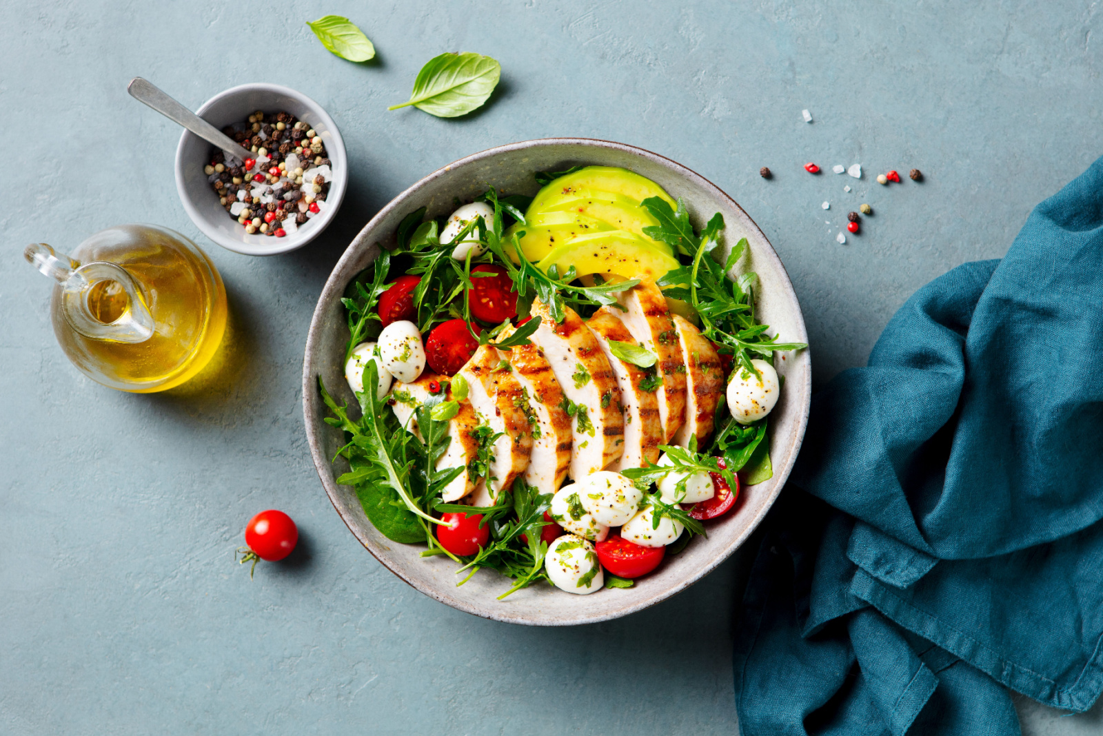 Warm grilled chicken salad with avocado and mozzarella cheese. Close up. Top view. Grey background.