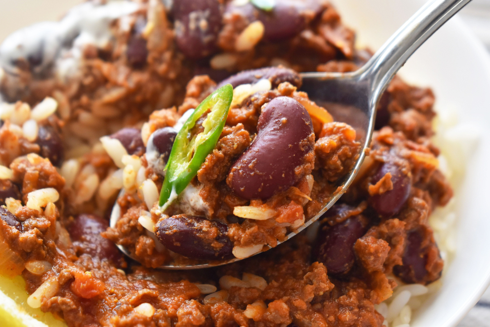 Chilli con carne with rice on spoon in a white bowl. Traditional Mexican food. 