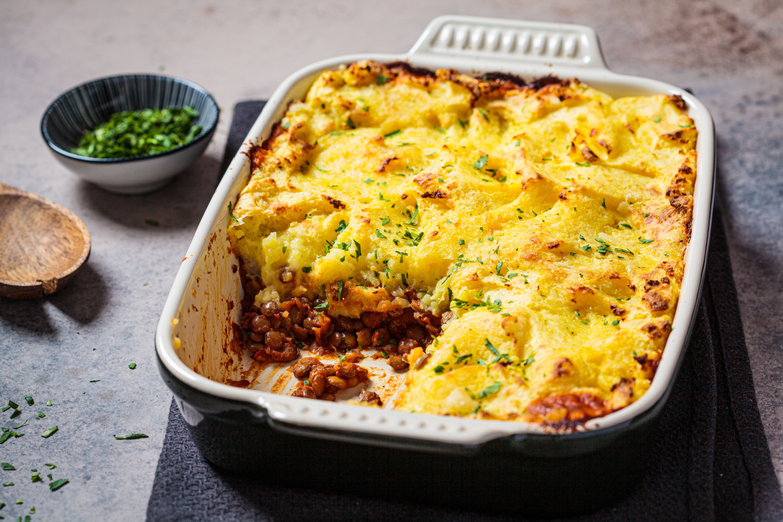 Vegan shepherd's pie with lentils and mashed potatoes in black backing dish. Vegan food concept.