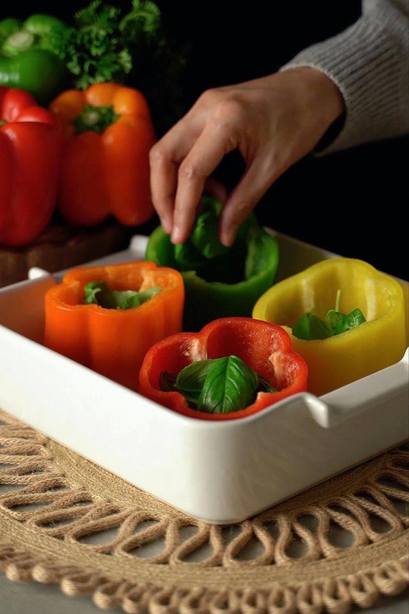 Close-up of a Person Putting Basil Leaves inside the Peppers on a Tray