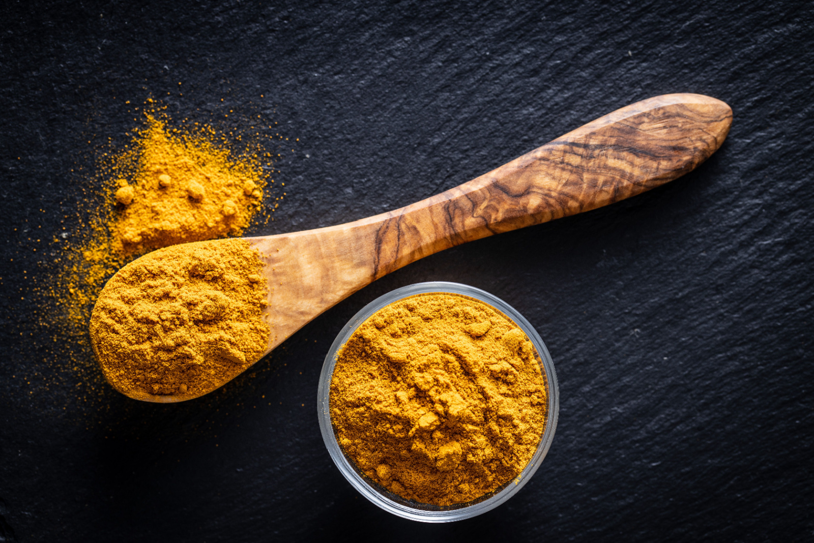 Indian turmeric powder. Turmeric spice. Ground turmeric in wooden spoon. Top view.