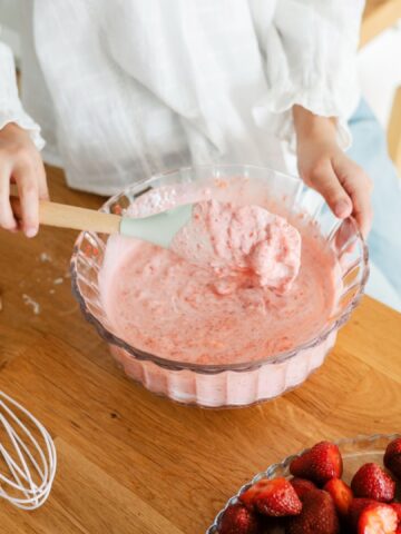 Homemade ice cream. Cute little girl preparing homemade strawberry ice cream at the kitchen. Summer food.