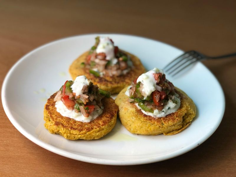 Zucchini Fritters with Tomatoes and Green Vegetables on White Ceramic Plate