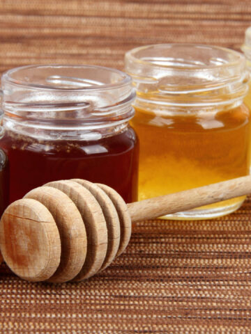 four jars full of honey wooden stick, mix taste