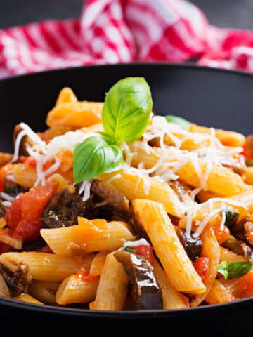 Pasta penne with eggplant. Pasta alla norma - traditional Italian food with eggplant, tomato, ricotta cheese and basil.