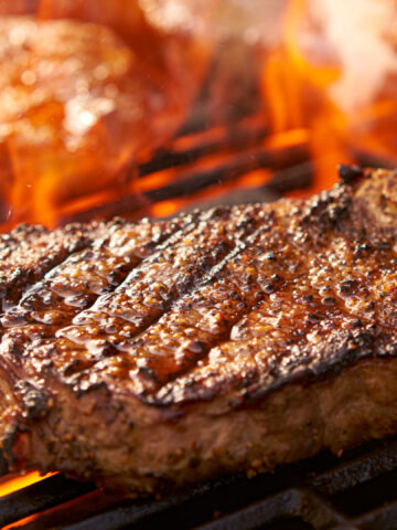 rib-eye steaks cooking on flaming grill panorama