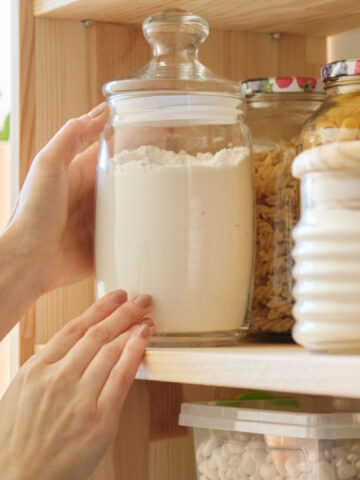 Food products in the kitchen storing ingredients in pantry. Woman taking jar of flour