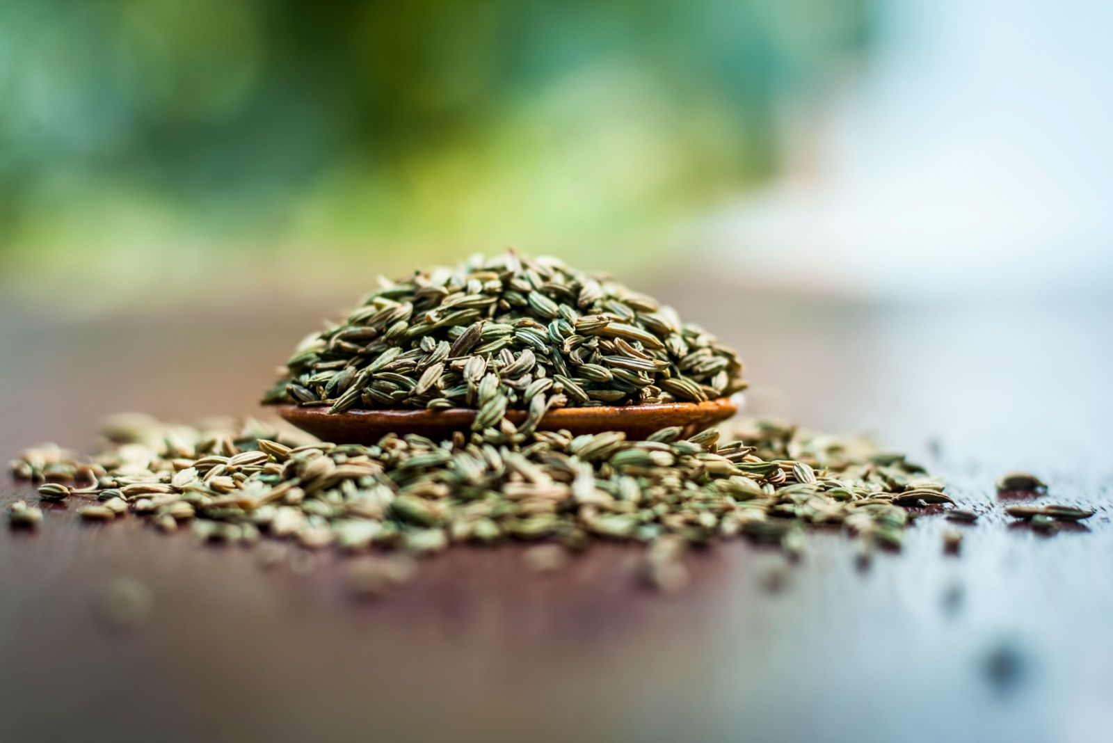 Raw dried fennel seeds or variyali or Foeniculum vulgare in a brown plate on wooden surface.