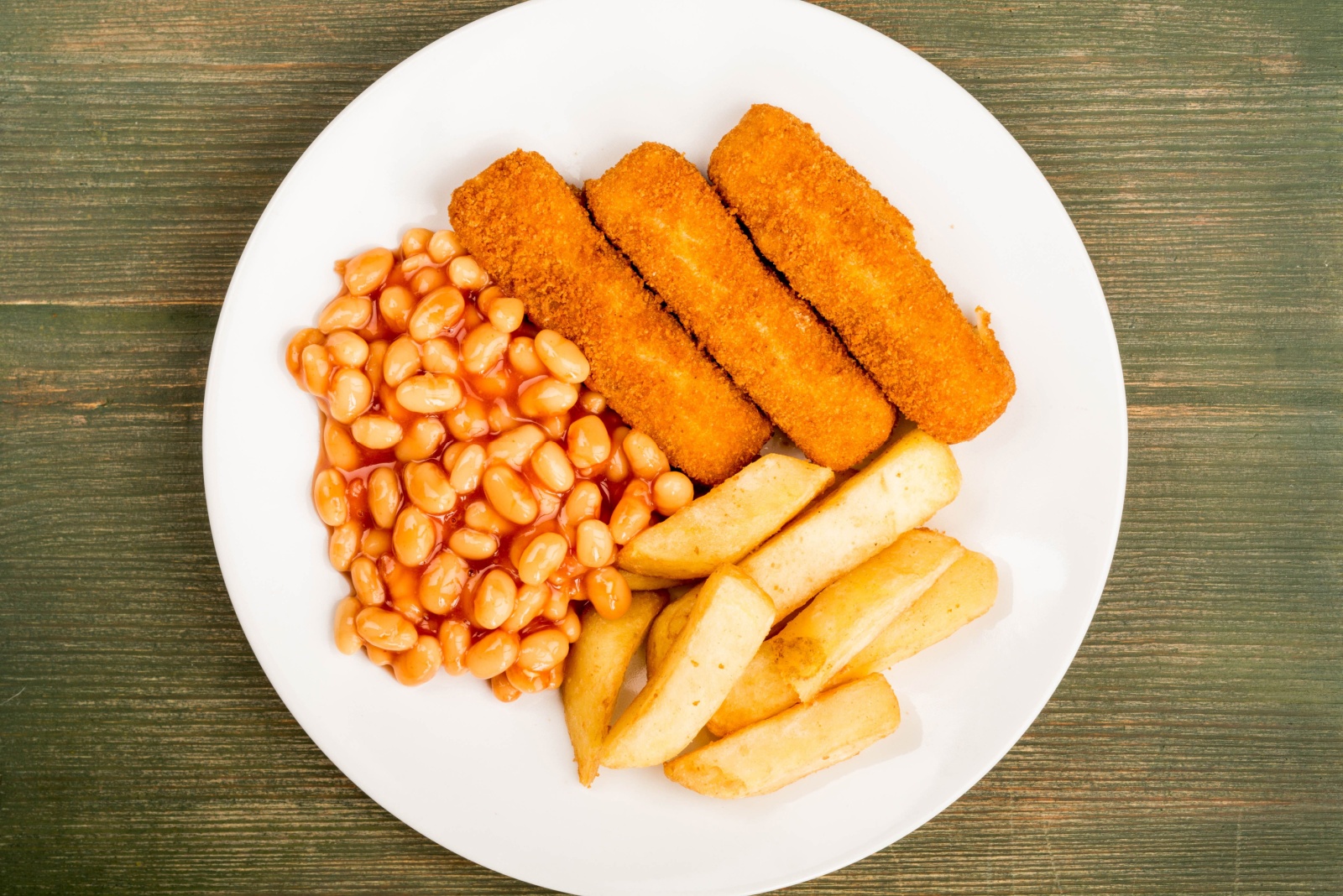 Grilled Cod Fish Fingers With Chunky Chips And Baked Beans in Tomato Sauce On A Green Wooden Background