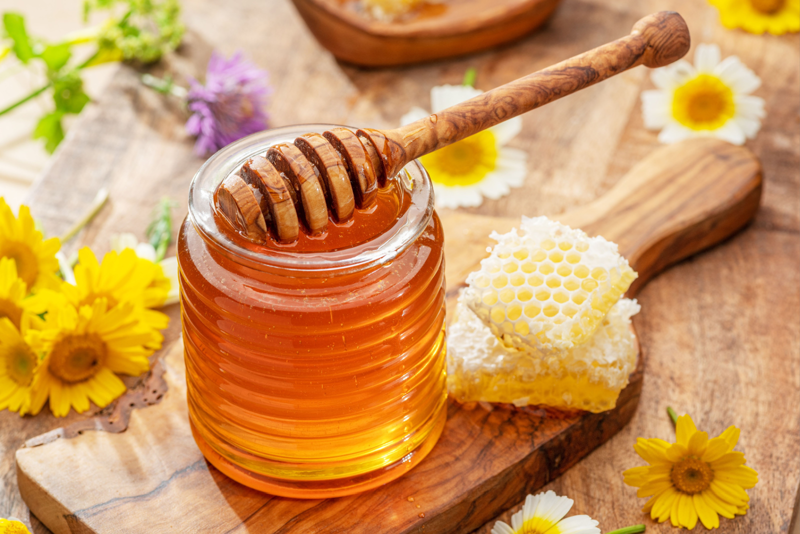 Natural organic honey in glass jar, honey dipper and honeycombs are near. Natural food background.