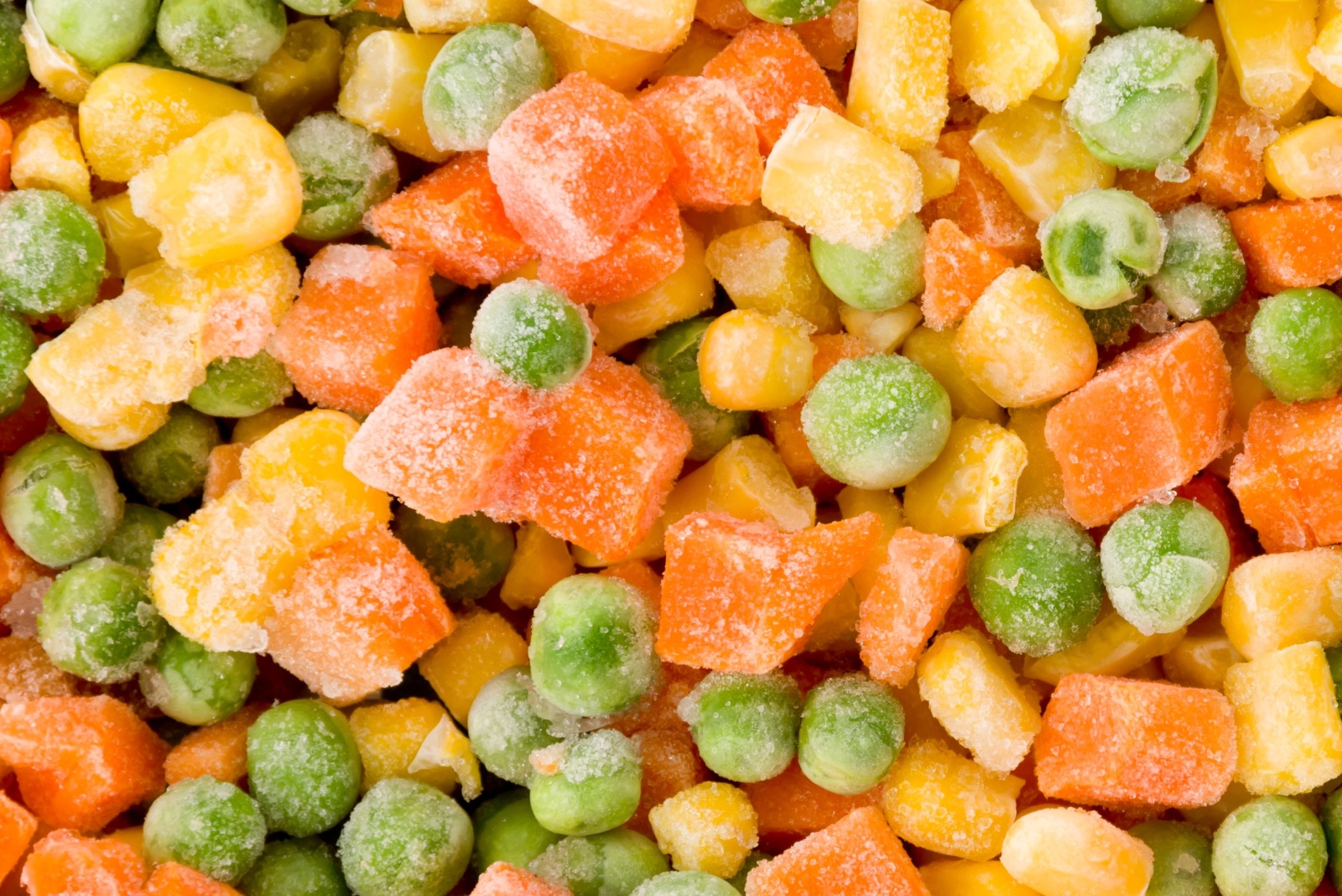 Frozen diced vegetables background with carrot, corn and peas.
