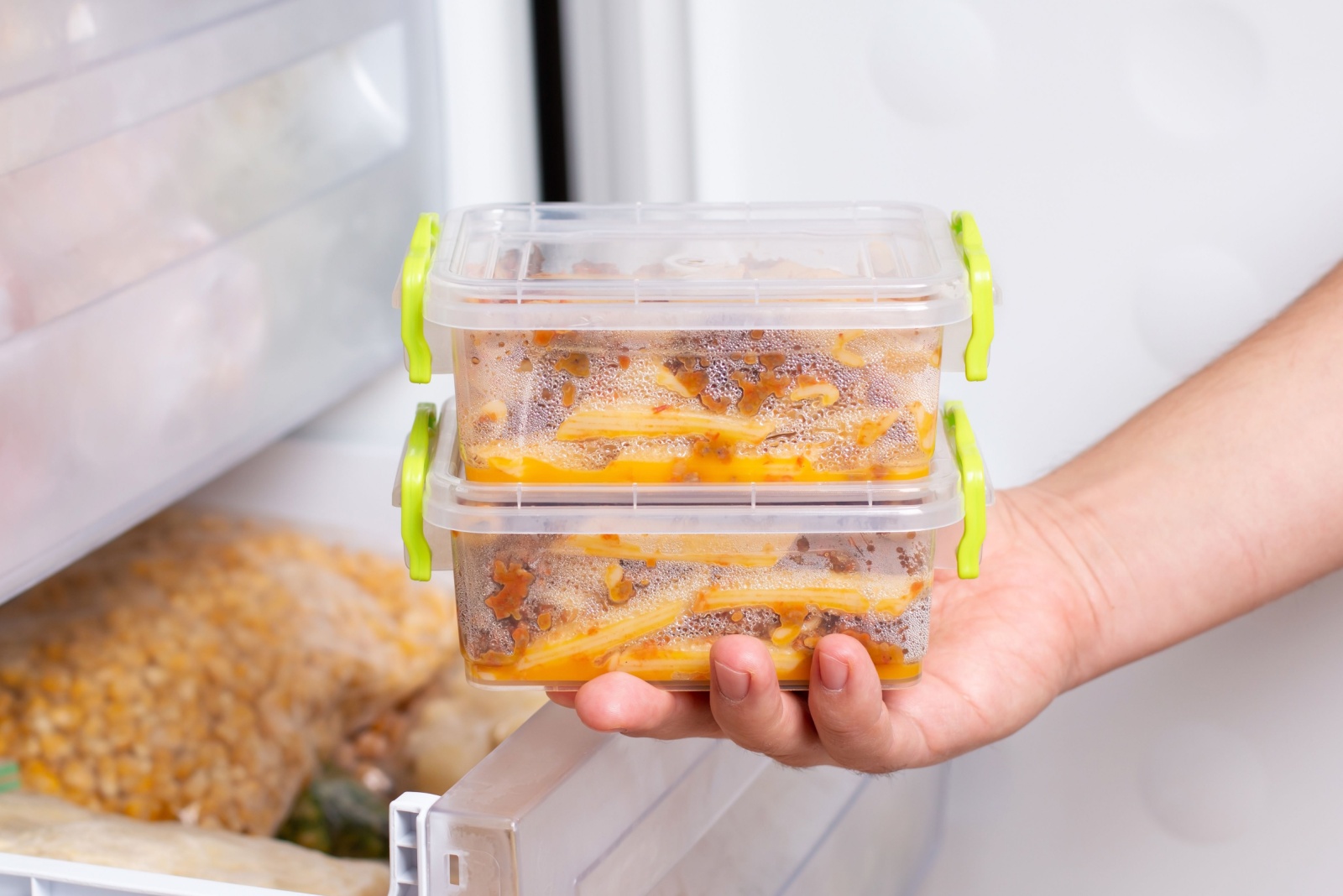 Ready frozen meal in a container in the refrigerator. Frozen food in the freezer. Fast cooking concept