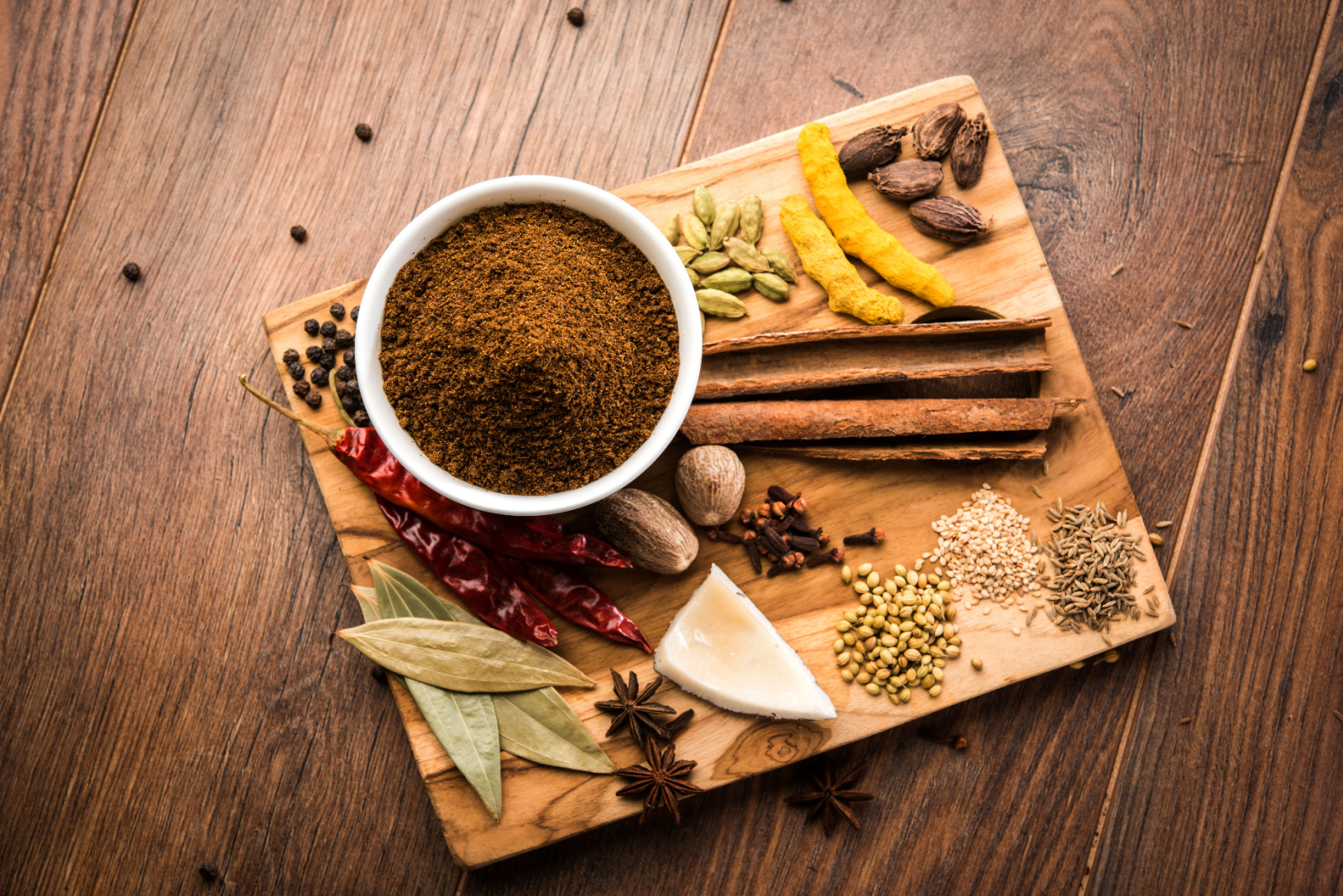 Indian Garam masala powder in bowl and it's ingredients colourful spices. Served over moody background. selective focus