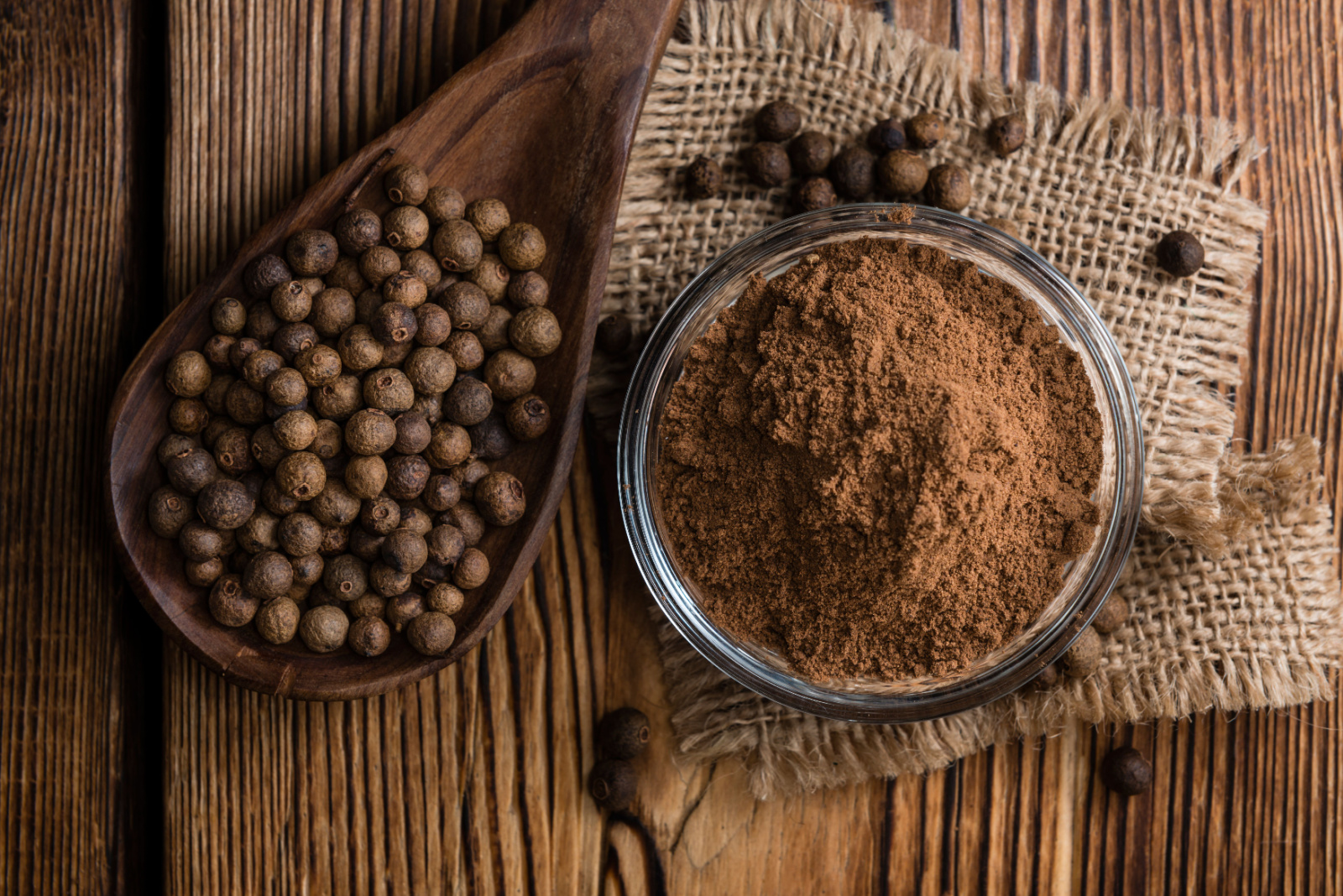 Portion of Allspice powder (detailed close-up shot) on wooden background