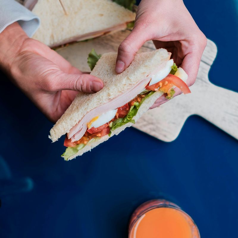Person showing delicious sandwich with piece of tomato
