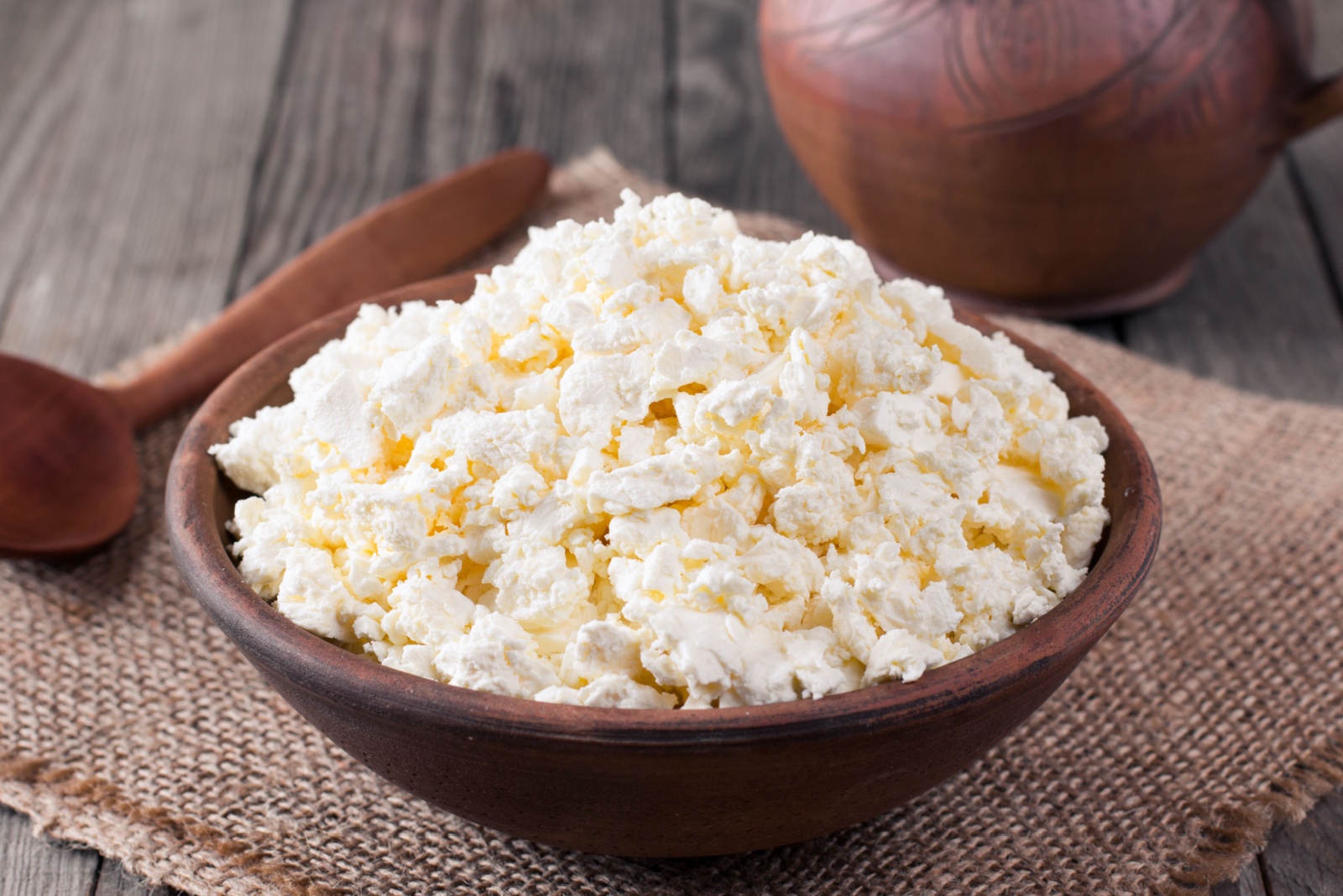 Homemade cottage cheese in a bowl on old wooden table