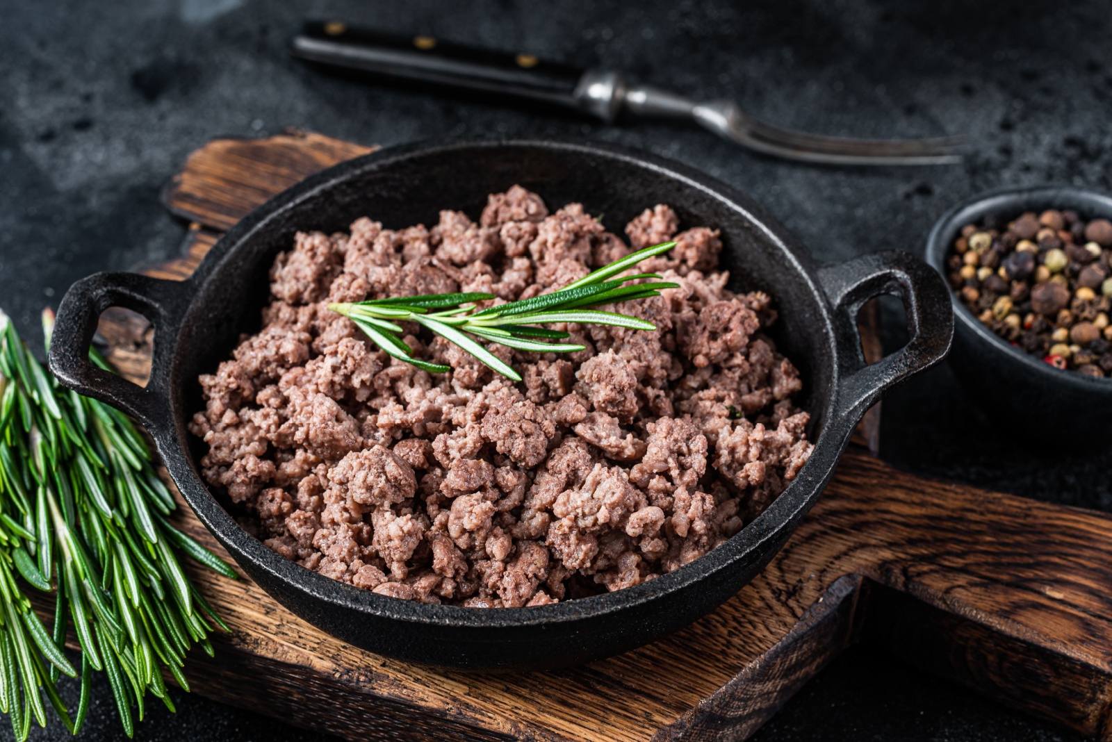 Fried mince beef meat in a pan for cooking pasta. Black background. Top view