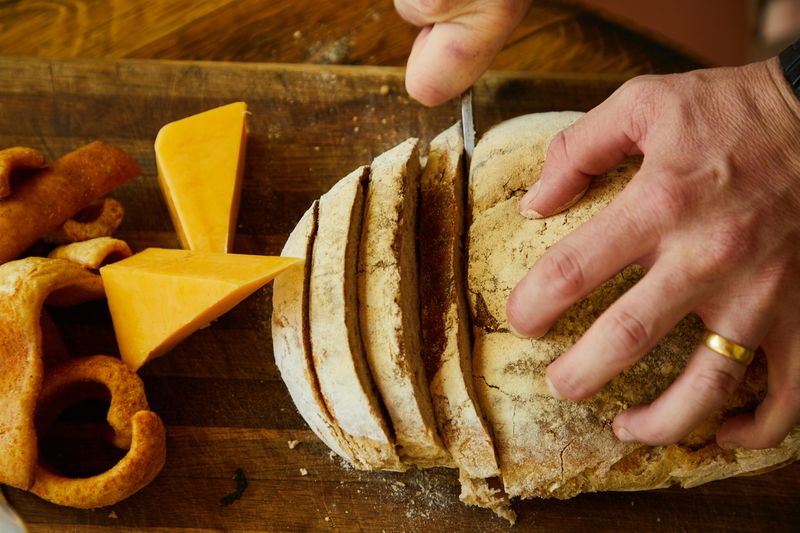 Person Cutting Fresh Bread on Board