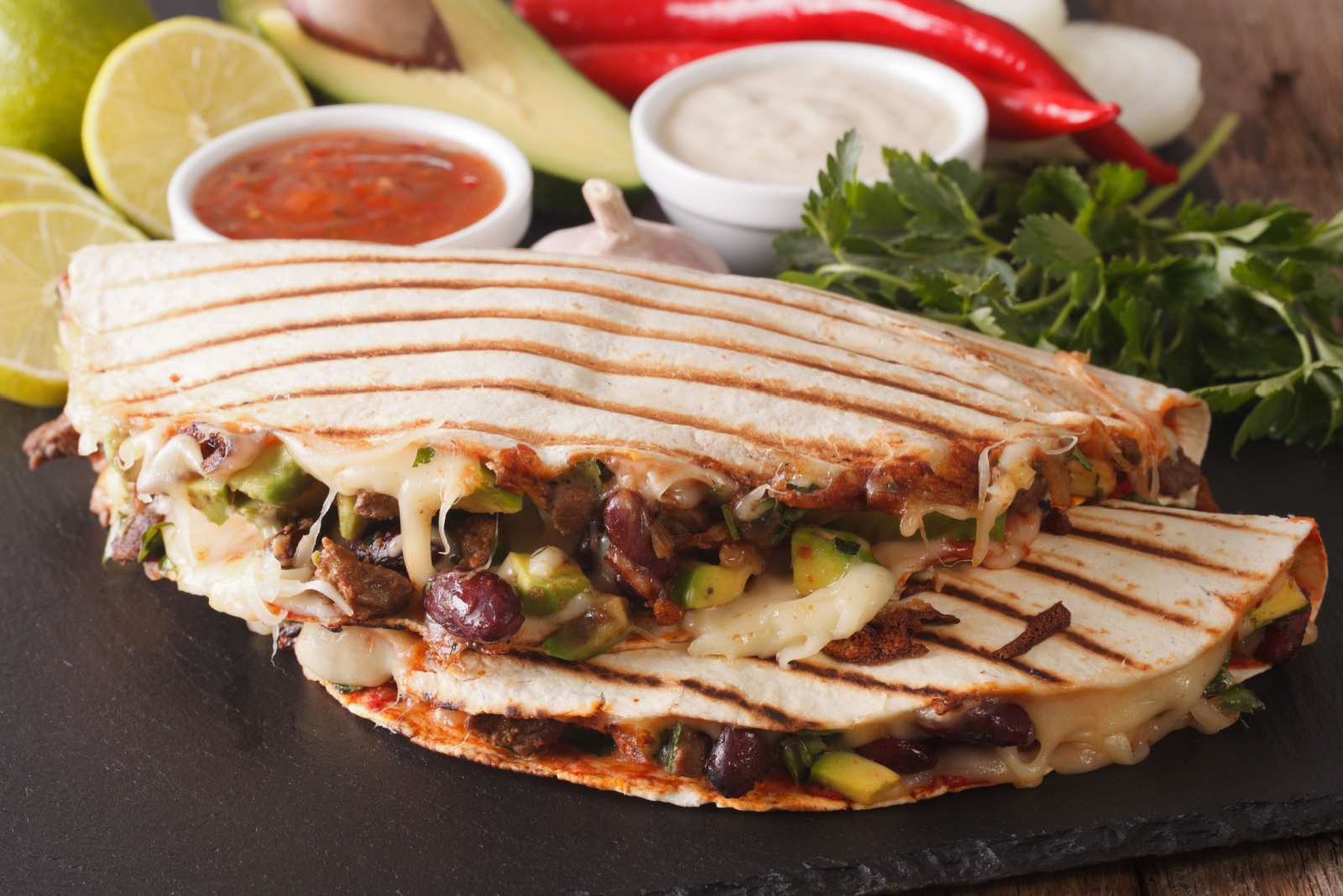 quesadilla with minced beef, beans, avocado and cheese close-up on the table. horizontal
