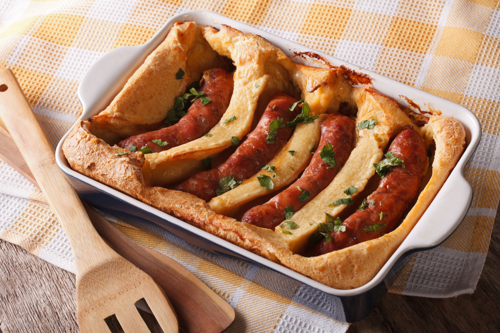 English food: toad in the hole into a baking dish close up on the table. Horizontal 