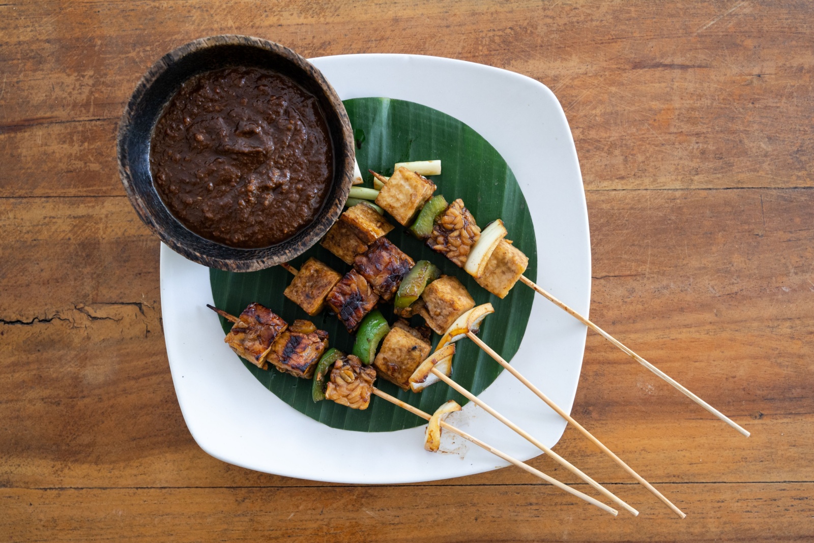 Top down view of vegan satay skewer with tofu and tempeh with peanut sauce, horizontal