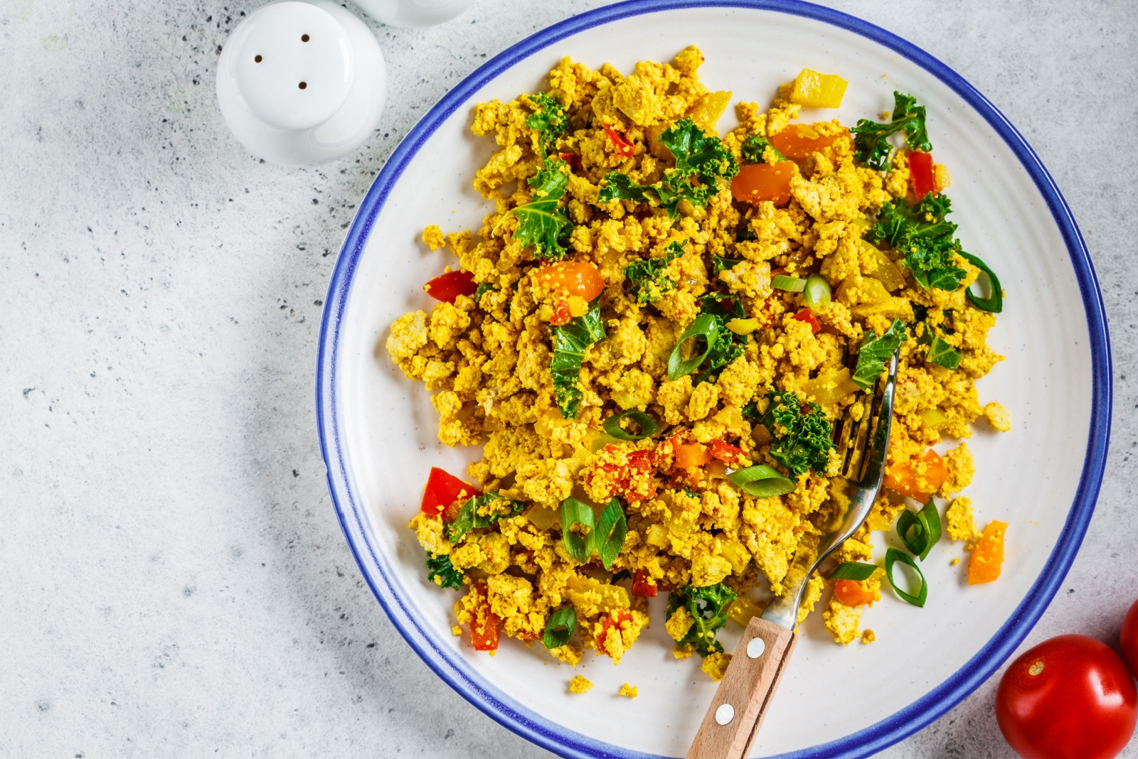 Tofu scramble with vegetables in white plate. Vegan Alternative food concept.