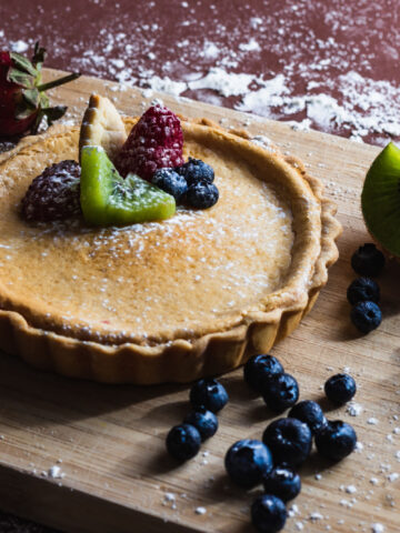 A closeup shot of treacle tart with blueberry, raspberry, strawberry and kiwi