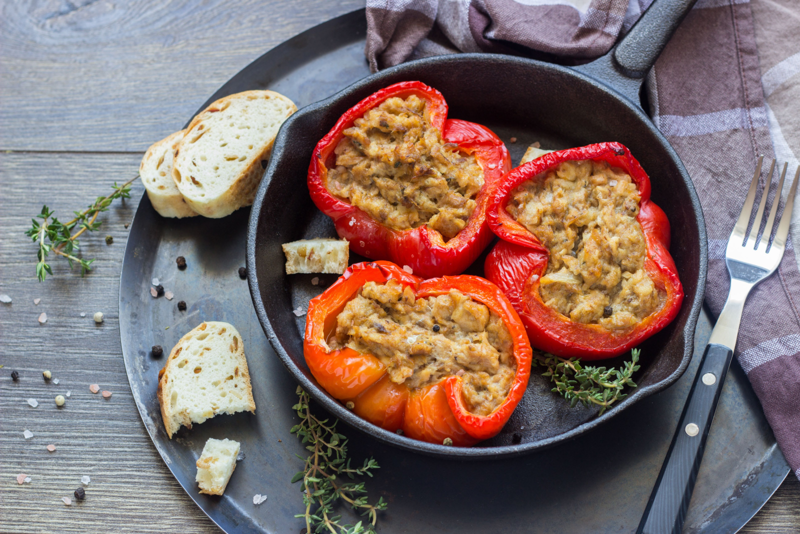 Baked sweet bell peppers stuffed with tuna and bread served in a frying pan.