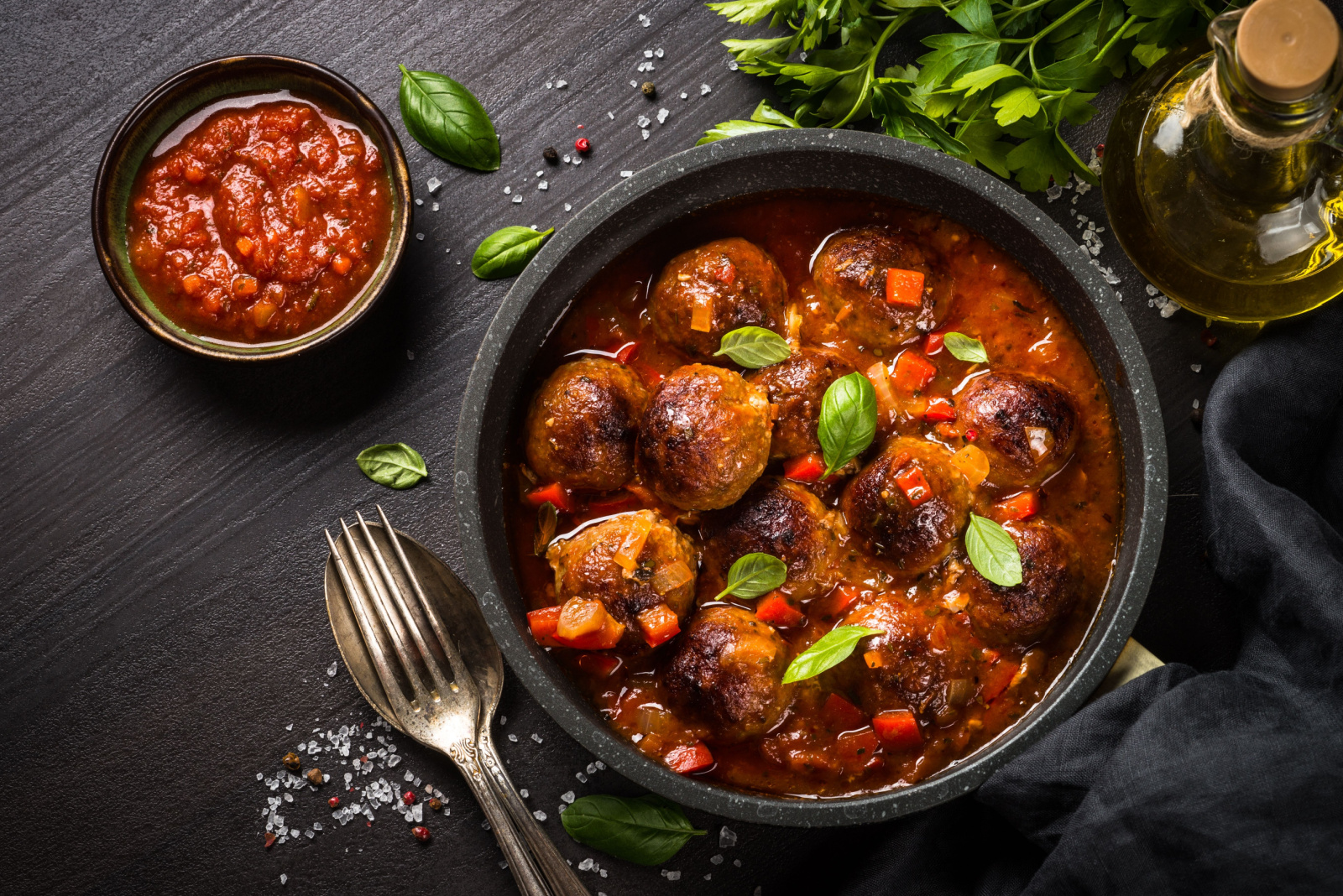 Meatballs in tomato sauce in a frying pan on dark wooden table.