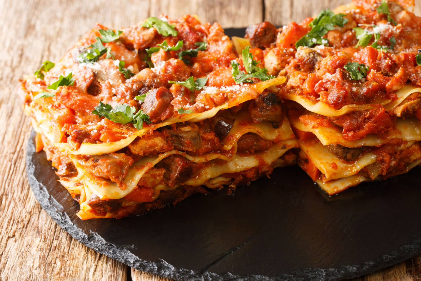 Lasagna Vincisgrassi Recipe with chicken giblets, beef, pork and vegetables close-up on a slate board on the table. horizontal 