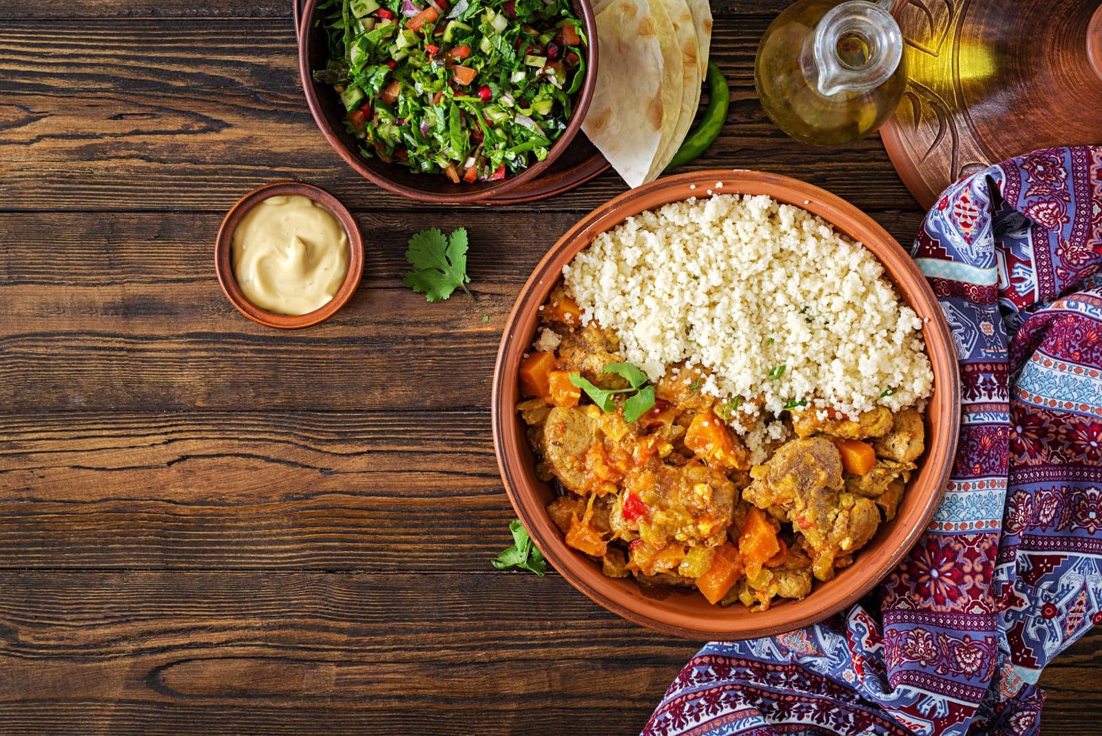 Traditional tajine dishes, couscous and fresh salad on rustic wooden table. Tagine lamb meat and pumpkin. Top view. Flat lay