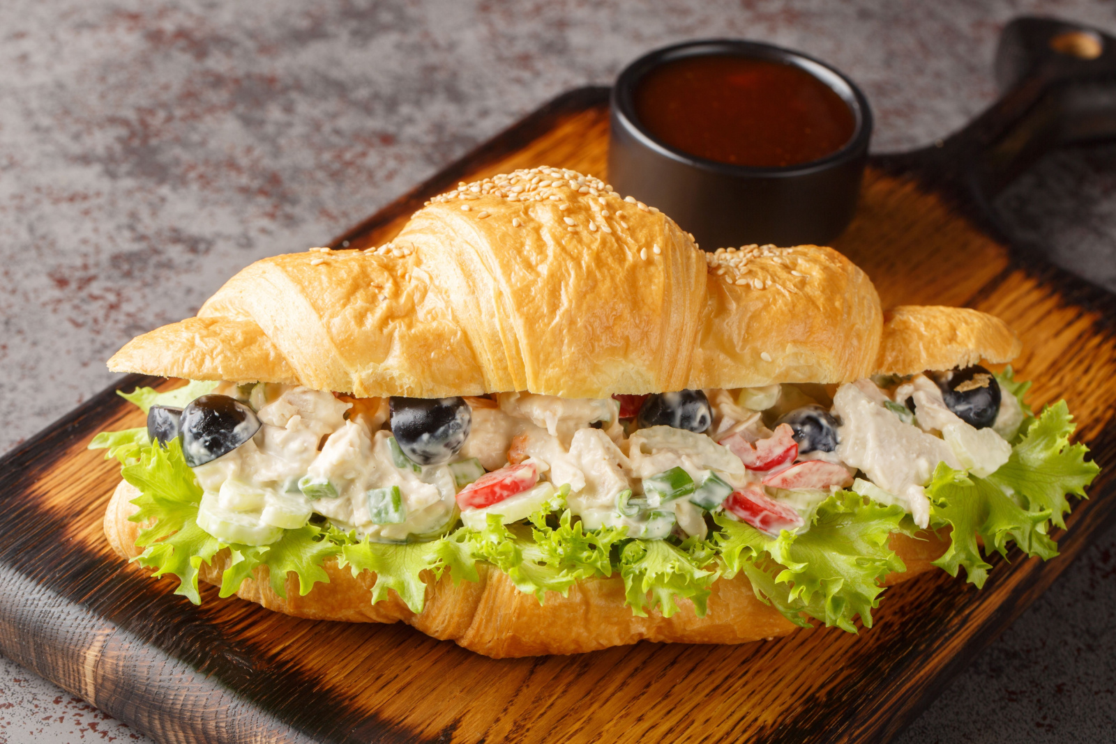 Homemade Healthy Chicken Salad Croissant Sandwich closeup on a wooden board on the table. Horizontal 