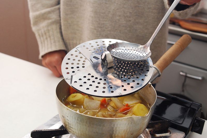 Dropping A Ceramic Weight Into A Pot To Keep Simmering Even
