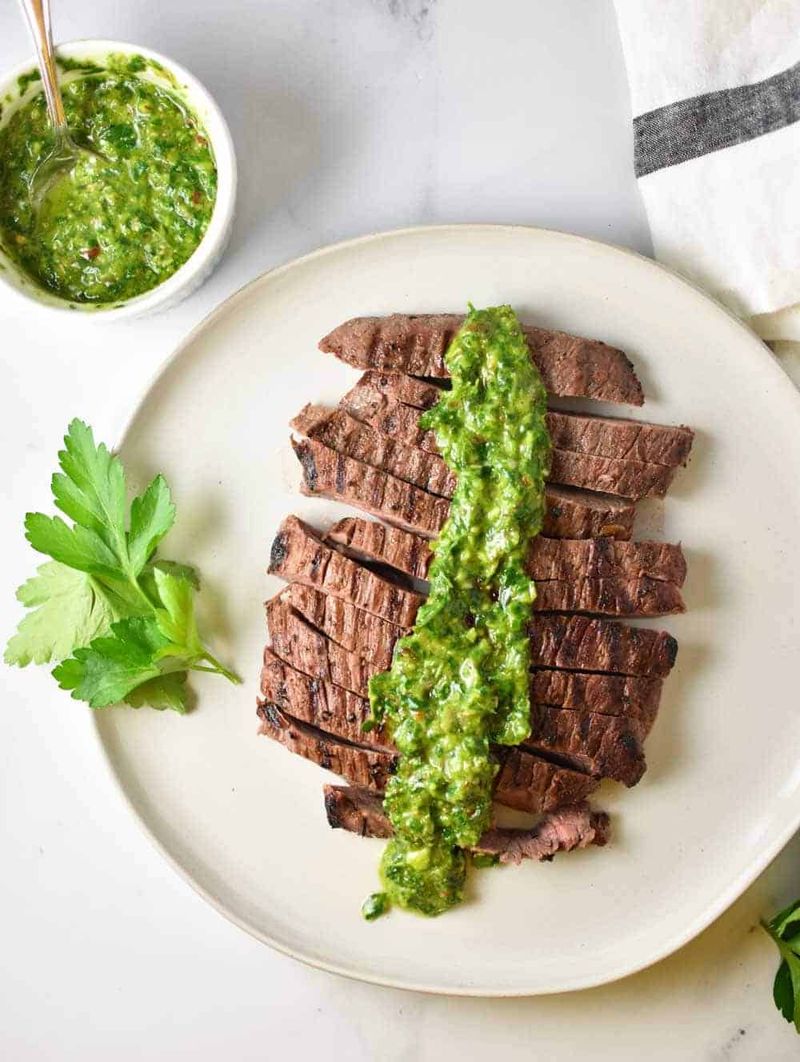 Sliced Steak with Chimichurri Drizzled on the Plate